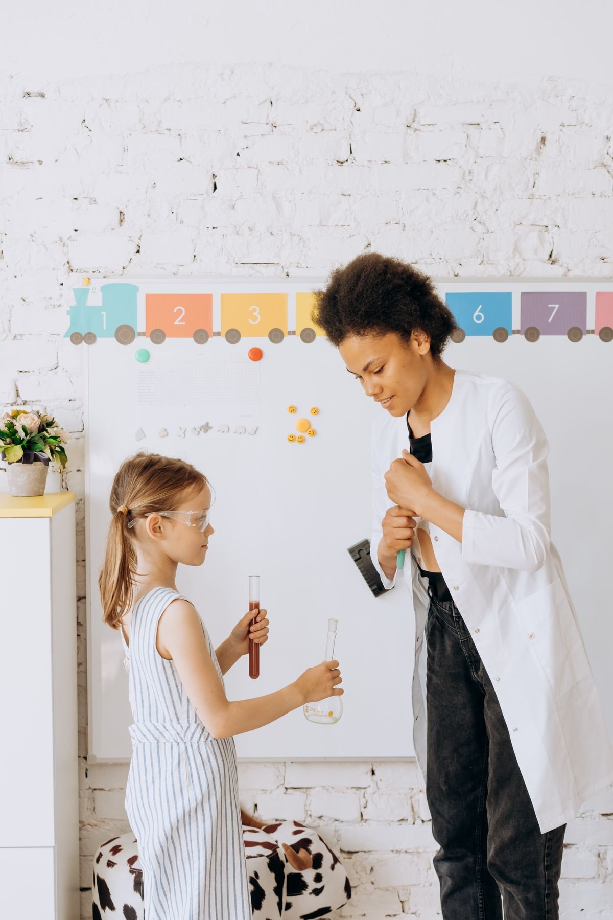 A learner wearing safety goggles explores a science experiment with a teacher